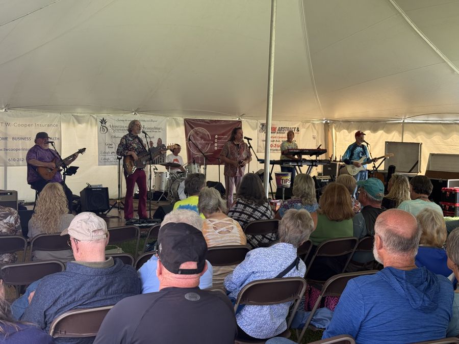 Live band playing to a seated crowd under the main tent at Community Day 2026