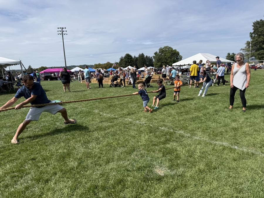 Kids and adults in a tug of war on the field at Community Day 2026